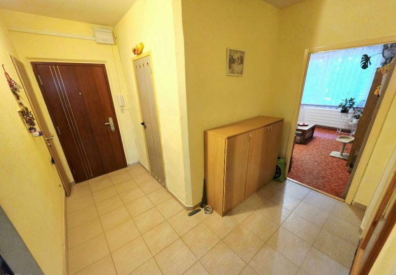 Flur in einer 4-Zimmer-Wohnung mit Eingangstür und Aufbewahrungsmöbeln.