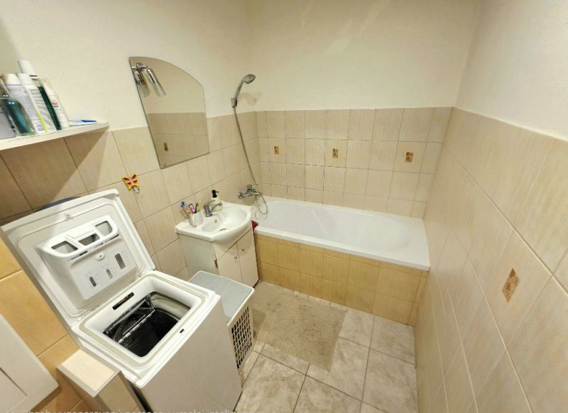 Badezimmer mit Waschmaschine, Badewanne und Waschbecken in einer 4-Zimmer-Wohnung.
