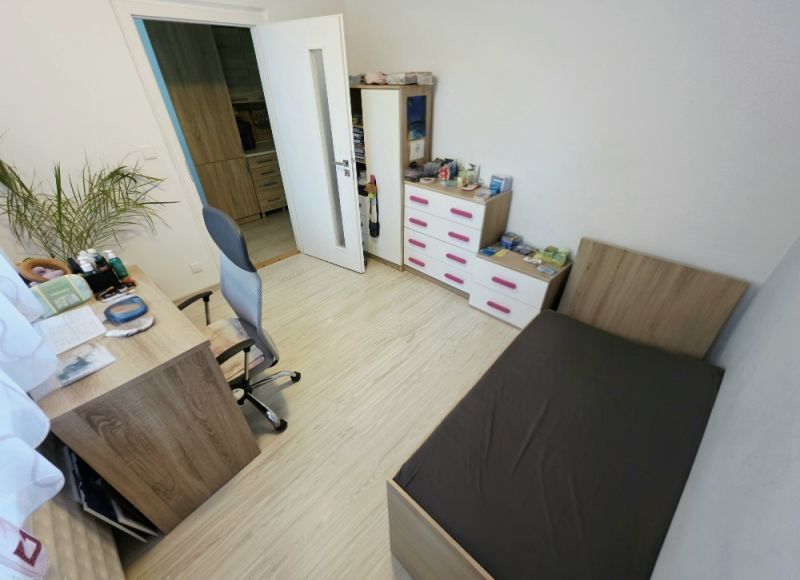 Ein Zimmer in einer 4-Zimmer-Wohnung mit Holzboden, Bett und Schreibtisch.