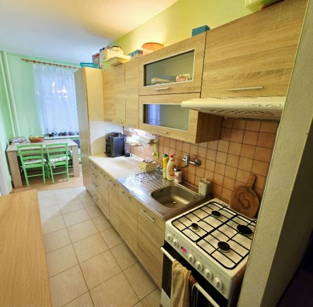 Küche in einer 4-Zimmer-Wohnung mit Holzelementen und Essecke.