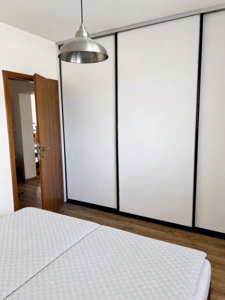 Schlafzimmer in einer 3-Zimmer-Wohnung mit Lampe, Kleiderschrank und Holzboden.