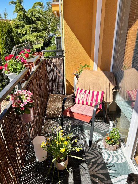 Balkon einer 3-Zimmer-Wohnung mit bequemen Sitzgelegenheiten, Blumen und Blick ins Grüne.