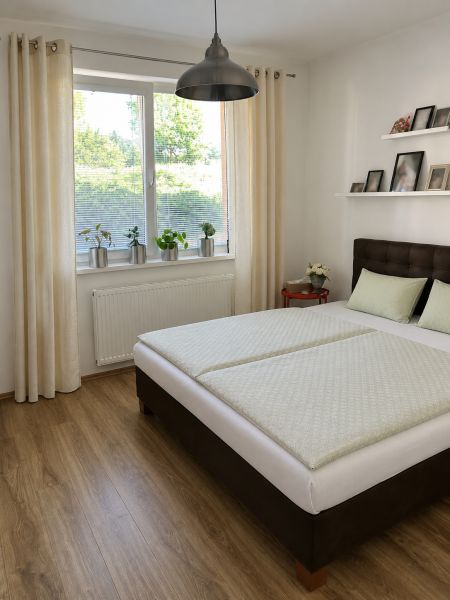 Schlafzimmer mit Holzboden, großem Fenster und einfachem Bett in einer 3-Zimmer-Wohnung.