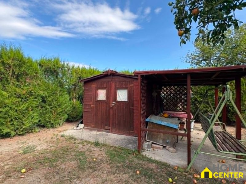 Ein hölzerner Pavillon und eine Schaukel im Garten in Komárno mit Obstbäumen.