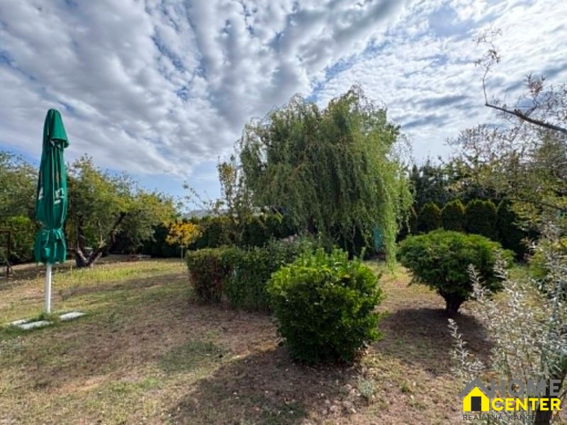 Ein Garten in Komárno mit Grün und einem Sonnenschirm unter einer bewölkten Himmel.