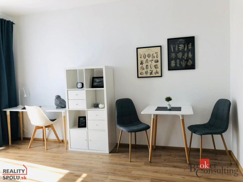 Innenraum einer Einzimmerwohnung mit Holzboden und stilvollen Stühlen.