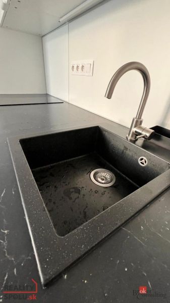 Küchenzeile mit Spüle und Armatur in einer Einzimmerwohnung.