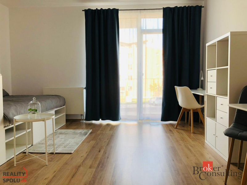 Einzimmerwohnung mit Holzboden, Bett, Tisch und weißen Möbeln.
