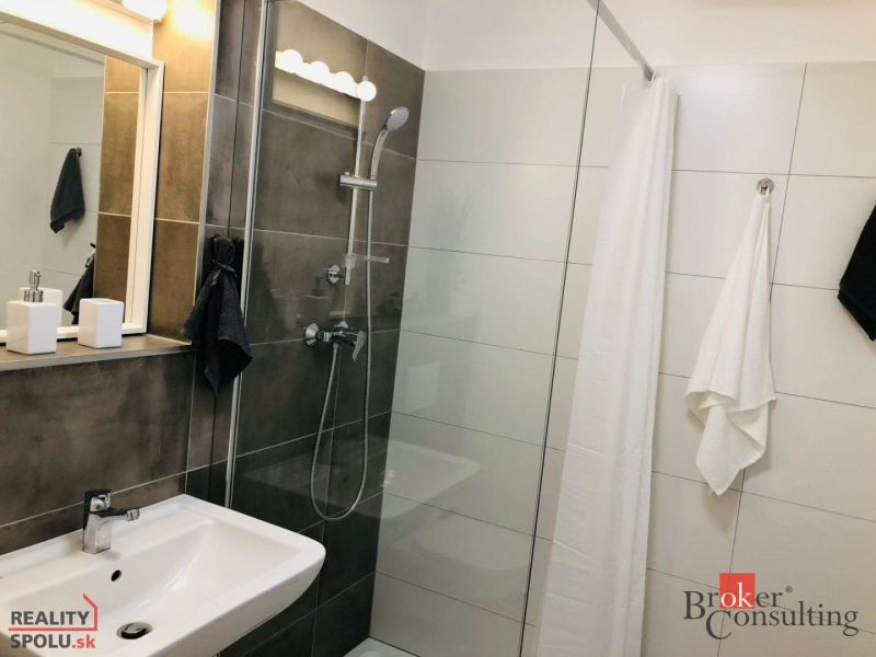 Badezimmer mit Dusche und Waschbecken in einer Einzimmerwohnung.