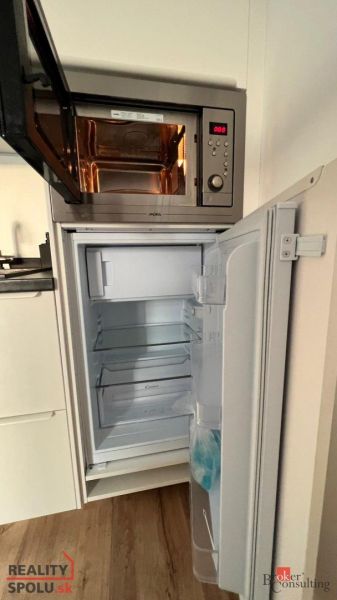 Küchenzeile mit Mikrowelle und offenem Kühlschrank. Boden mit Holzdekor.