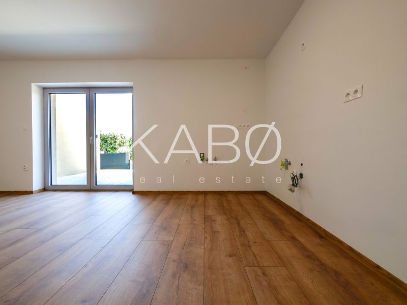 Ein Zimmer in einem Einfamilienhaus mit einem Boden in Holzoptik und Zugang zur Terrasse.