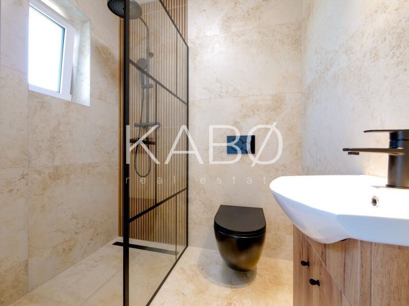 Ein Badezimmer in einem Einfamilienhaus mit einer modernen Duschkabine und einer schwarzen Toilette.