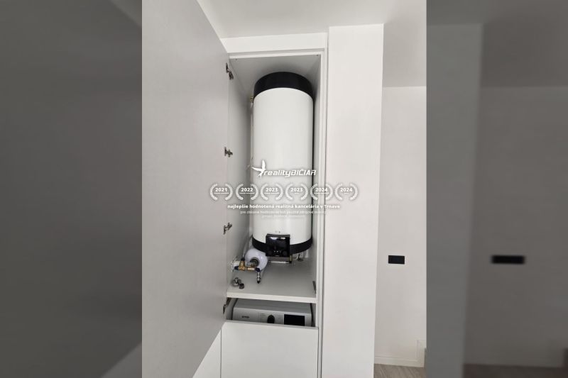 Boiler im Schrank in der Villa, weiße Wand, einfaches Interieur.