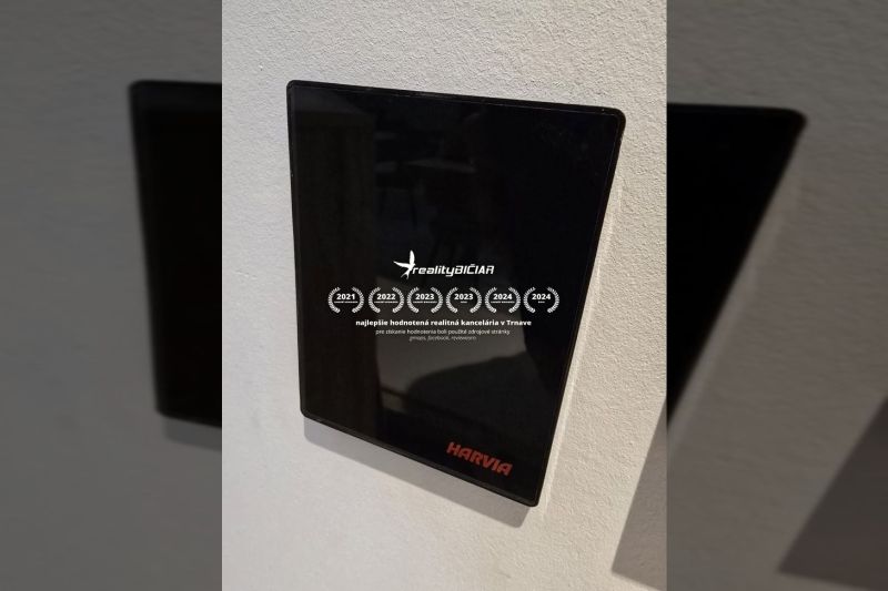 Schwarzes Harvia-Display an der Wand im Inneren der Villa mit Auszeichnungen des Immobilienbüros.