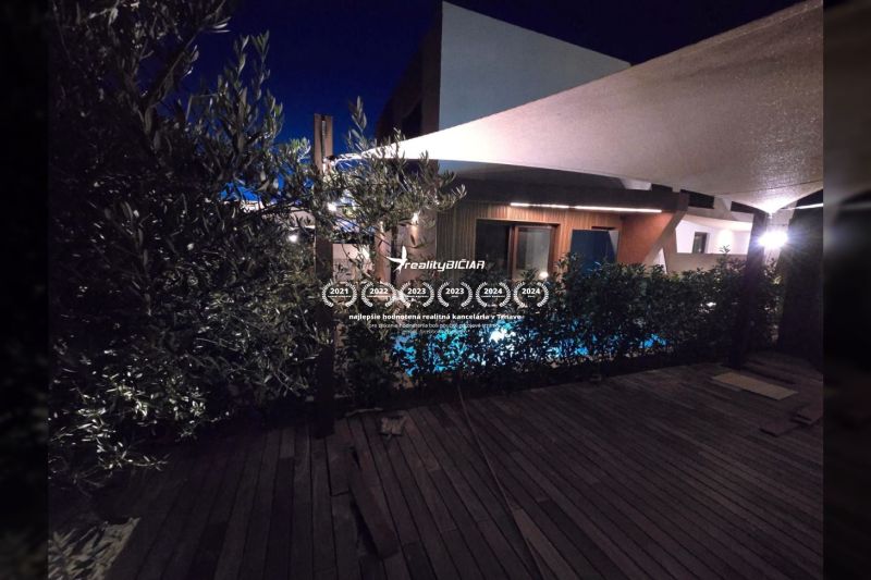 Nachtgarten der Villa in Nine mit Pool und Boden in Holzoptik.