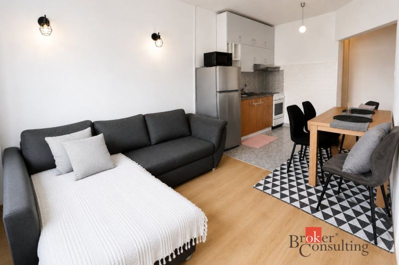 Stilvolles Interieur einer 2-Zimmer-Wohnung mit Holzboden, Küche und Esstisch.