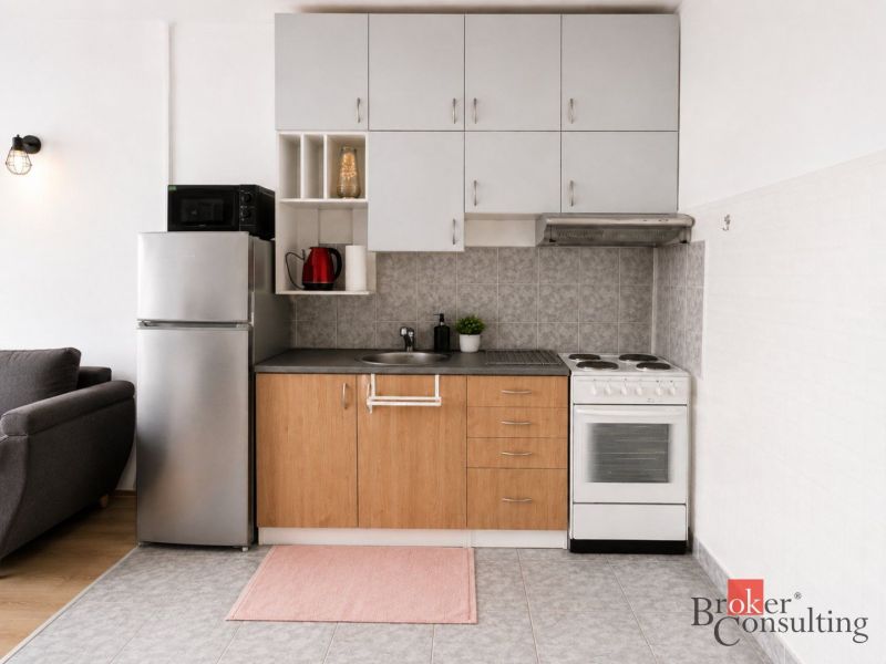Küche in einer 2-Zimmer-Wohnung mit Geräten und Boden in Holzoptik.