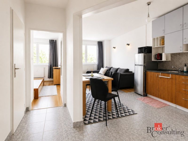 Innenraum einer 2-Zimmer-Wohnung mit Küche, Esstisch und Boden mit Holzdekor.