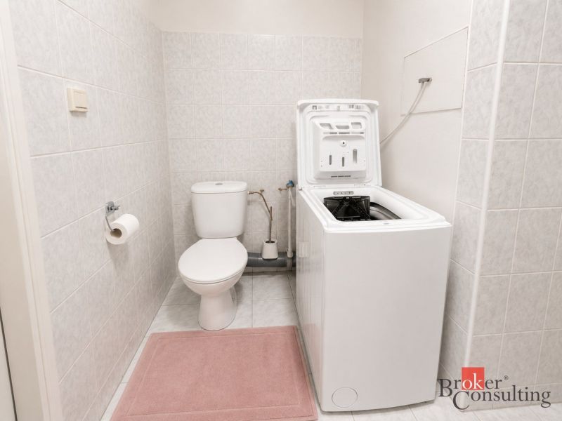 Badezimmer in einer 2-Zimmer-Wohnung mit Waschmaschine und WC auf Fliesen.