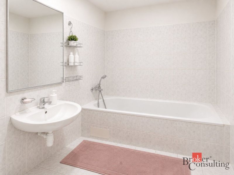 Badezimmer in einer 2-Zimmer-Wohnung mit Badewanne, Waschbecken und hellem Fliesenbelag.