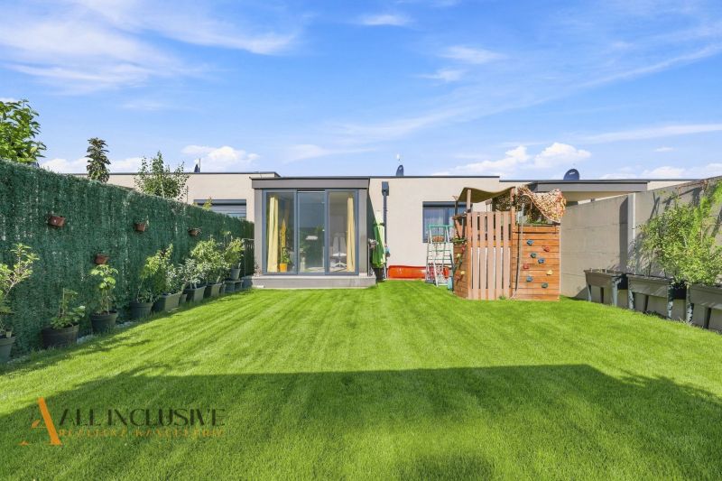 Der Garten des Einfamilienhauses in Oľdza mit Rasen, Kinderspielplatz und Pflanzen in Blumentöpfen.