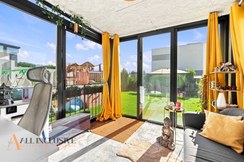 Ein sonniger Raum in einem Einfamilienhaus mit Blick auf den Garten durch Glastüren.