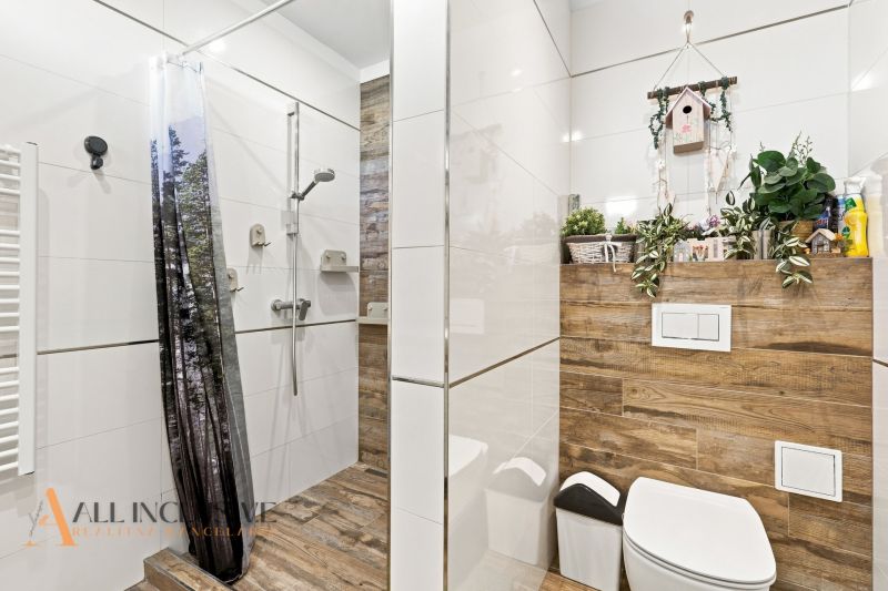 Ein Badezimmer in einem Einfamilienhaus mit einem Boden in Holzoptik und einer Duschkabine mit Vorhang.