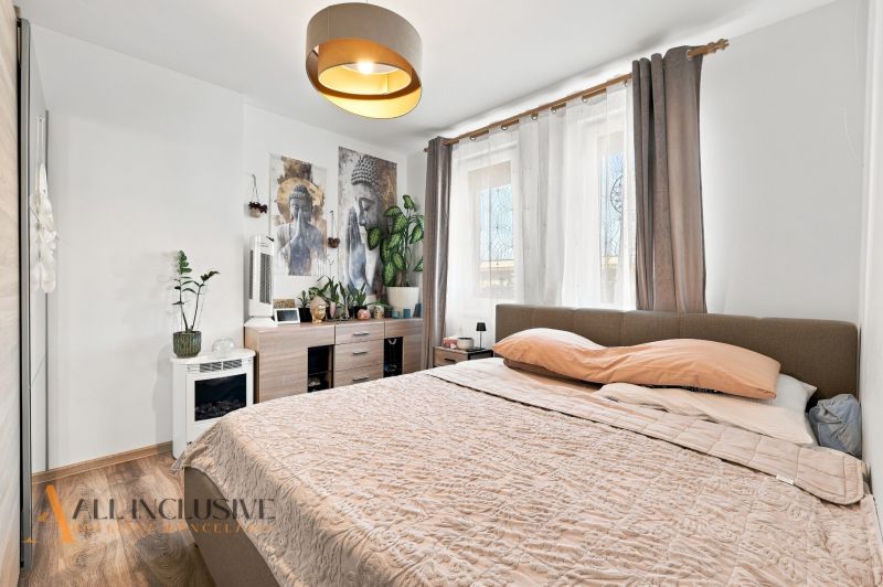 Schlafzimmer mit hellen Wänden, Bett und Dekorationen, Boden mit Holzdekor.