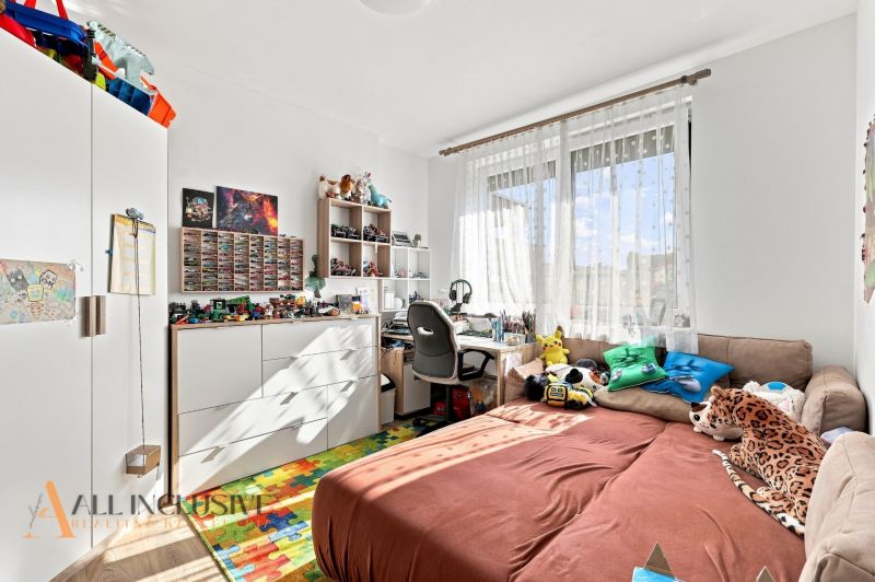 Kinderzimmer in einem Einfamilienhaus mit Spielzeug, gemustertem Teppich und Schreibtisch.