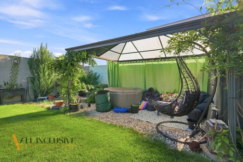 Der Garten eines Einfamilienhauses in Oľdza mit einer Pergola, Vorhängen und einer Schaukel zur Entspannung.