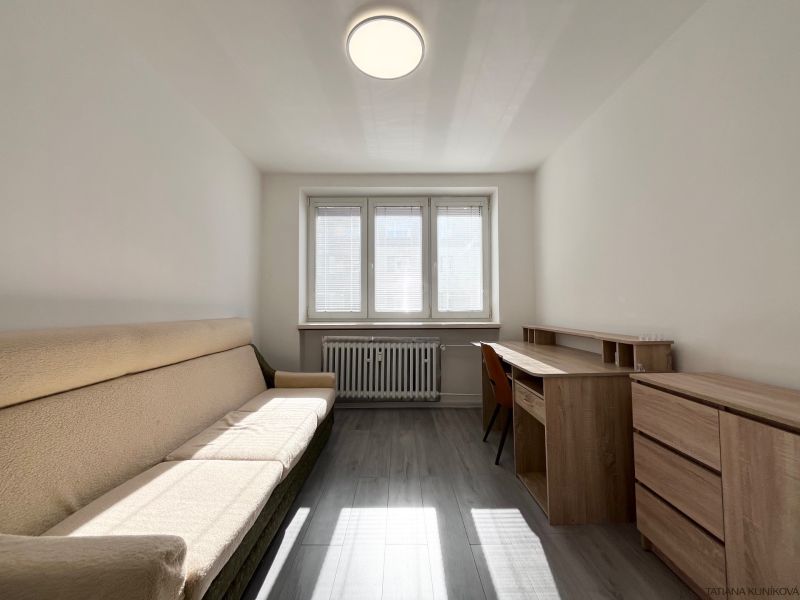 Ein Zimmer in einer 3-Zimmer-Wohnung mit einem Sofa, einem Schreibtisch und einem Holzboden.