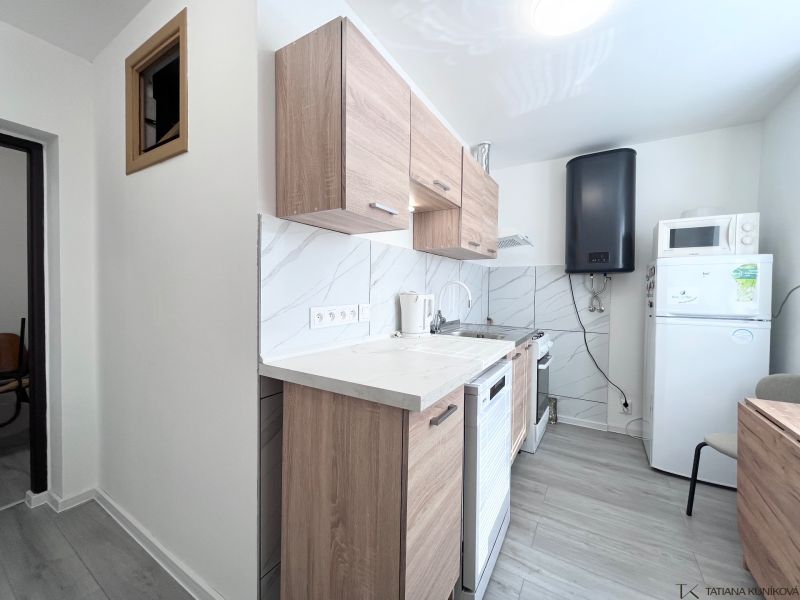 Küche in einer 3-Zimmer-Wohnung mit Holzboden und weißen Geräten.