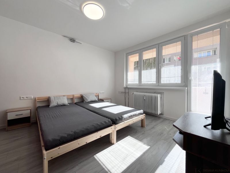 Helles Schlafzimmer mit Bett, Fernseher und Holzboden in einer 3-Zimmer-Wohnung.