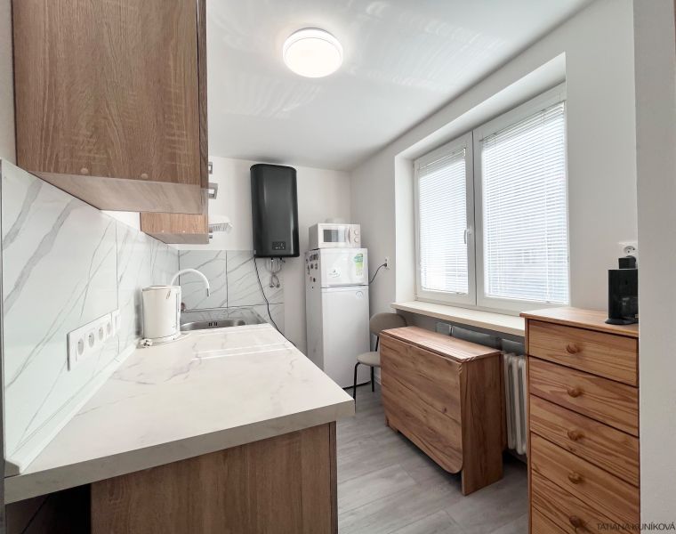 Küche in einer 3-Zimmer-Wohnung mit Fliesen und Holzschränken.