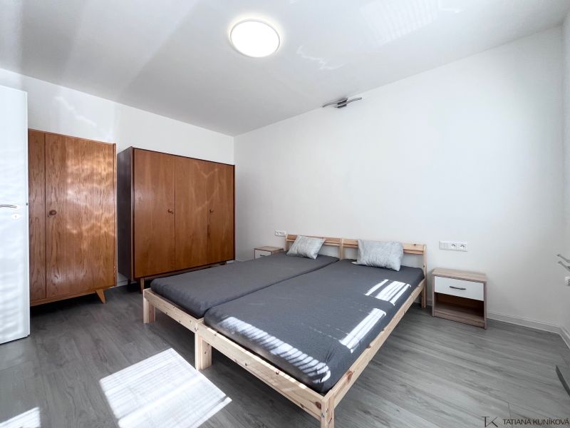 Schlafzimmer mit Bett, Holzschränken und Boden mit Holzdekor in einer 3-Zimmer-Wohnung.