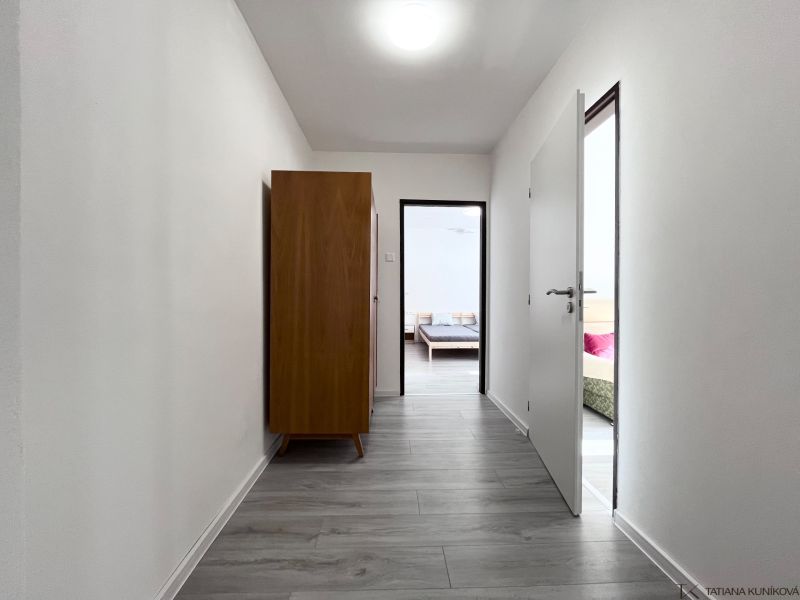 Flur mit Holzboden in einer 3-Zimmer-Wohnung, dunkler Schrank, Türen zu den Zimmern.