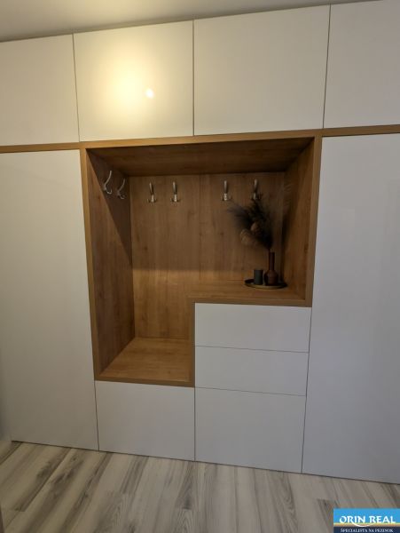 Weißer Einbauschrank mit Holzdekor und Kleiderhaken in einer 2-Zimmer-Wohnung.