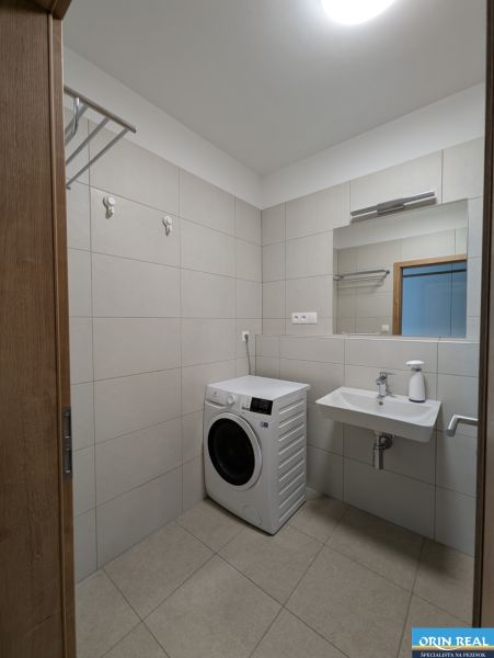 Badezimmer mit Waschmaschine und Waschbecken in einer 2-Zimmer-Wohnung.
