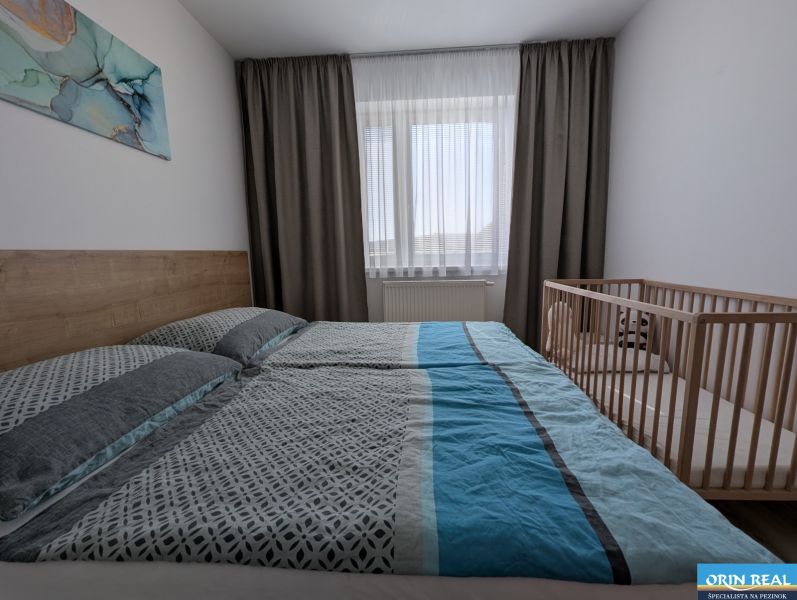 Helles Schlafzimmer mit Bett und Kinderbett in einer 2-Zimmer-Wohnung.