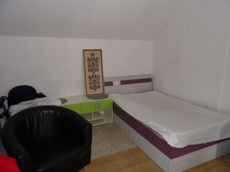 Ein Zimmer in einer 2-Zimmer-Wohnung mit einem Bett, einem Sessel und einem Boden in Holzoptik.
