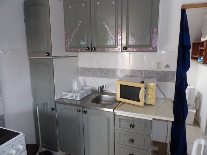 Küchenbereich in einer 2-Zimmer-Wohnung mit Mikrowelle und dekorierten Schränken.