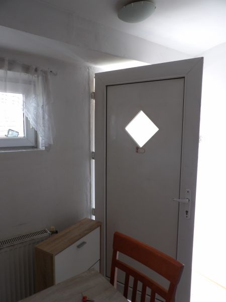 Eingangstür in einer 2-Zimmer-Wohnung mit Holzdekor der Kommode und des Stuhls.
