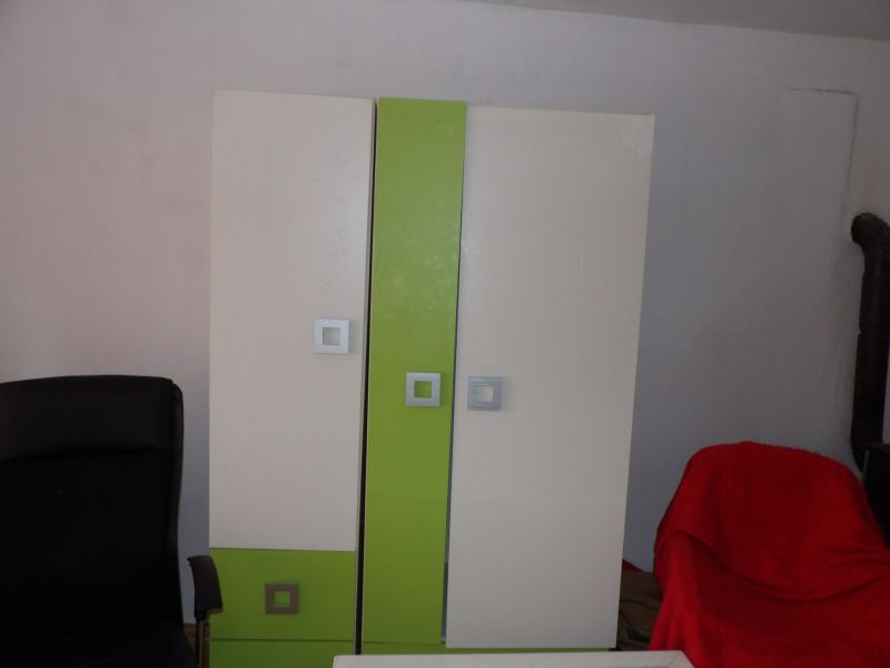 Ein Kleiderschrank mit bunten Türen und ein schwarzer Sessel in einer Zweizimmerwohnung.