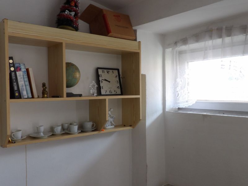Ein Regal mit Souvenirs und Büchern in einer 2-Zimmer-Wohnung mit Licht aus dem Fenster.