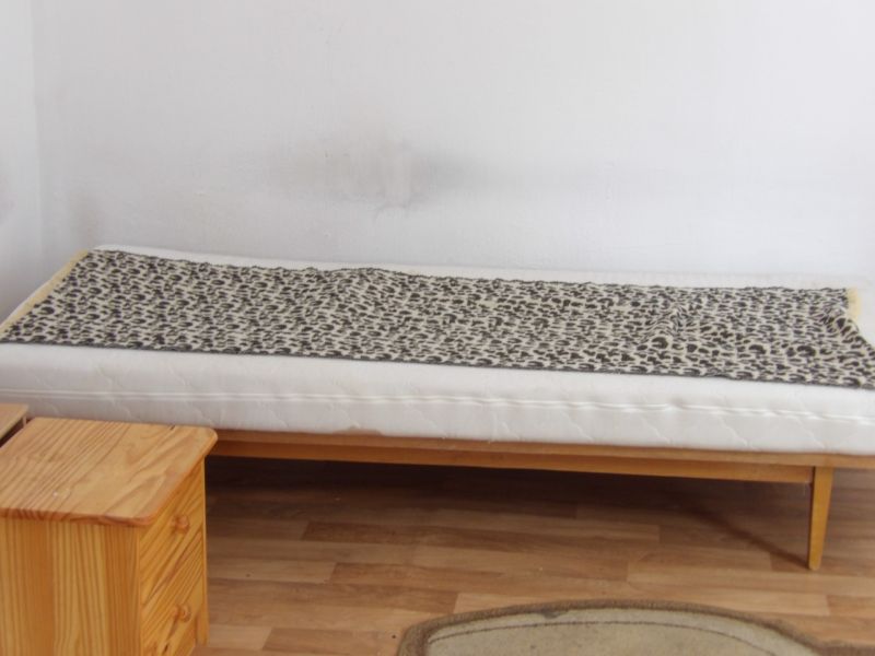 Ein Bett in einem Zimmer mit einem Holzboden, daneben ein Holzschrank.