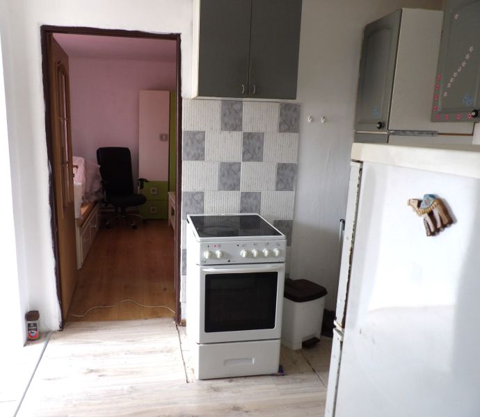 Küche in einer 2-Zimmer-Wohnung, mit Blick auf den Wohnraum mit Holzboden.