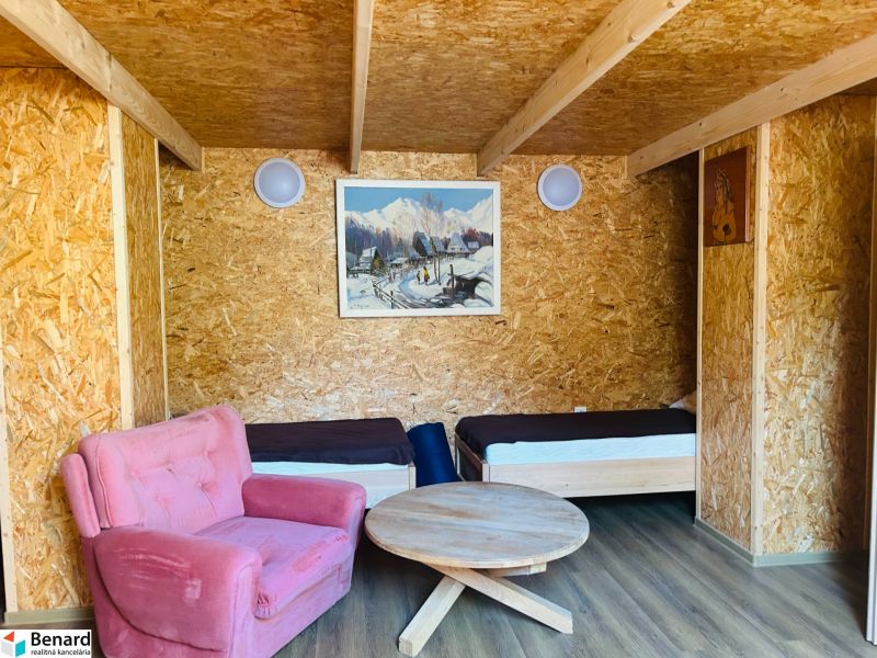 Ein Zimmer in einem Einfamilienhaus mit zwei Betten, einem rosa Sessel und einem Boden in Holzoptik.