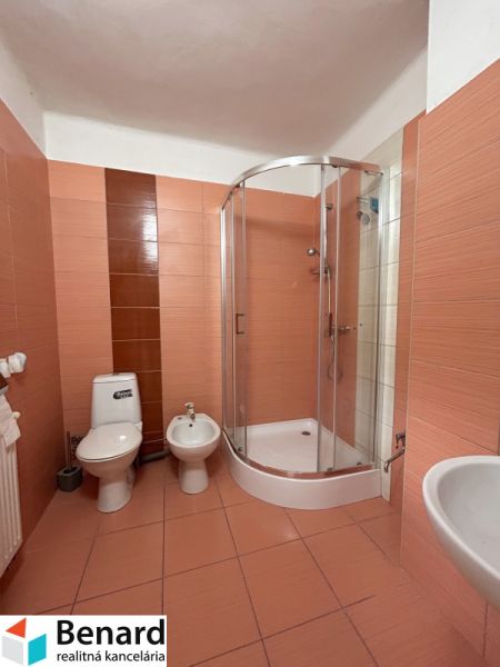 Badezimmer im Einfamilienhaus: Duschkabine, Toilette, Bidet, Fliesen in warmen Tönen.