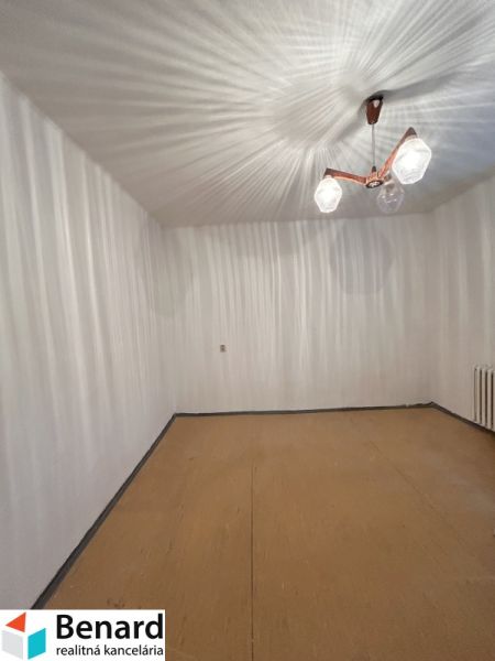 Ein Zimmer in einem Einfamilienhaus mit weißen Wänden und einem Boden in Holzoptik.