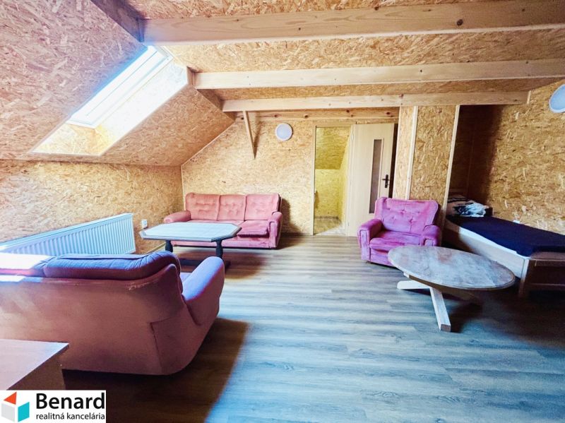 Wohnzimmer eines Einfamilienhauses mit Holzboden und rosa Sesseln.